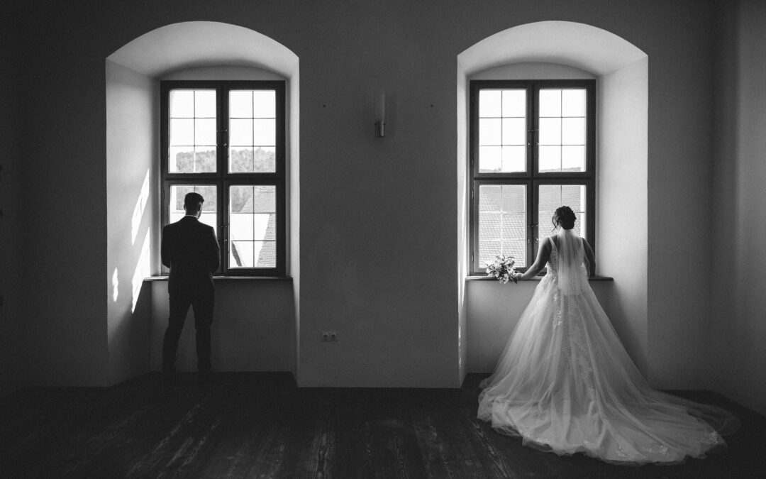 Braut & Bräutigam stehen am Fenster mit dem Rücken zur Kamera